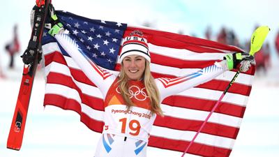 Mikaela Shiffrin holds up an American flag while celebrating at the 2018 Olympics